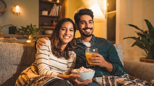 couple regardant la TV avec popcorns et boisson